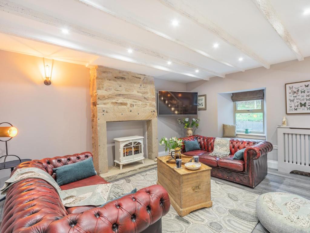 sala de estar con 2 sofás y chimenea en Burnside Cottage en Bardon Mill