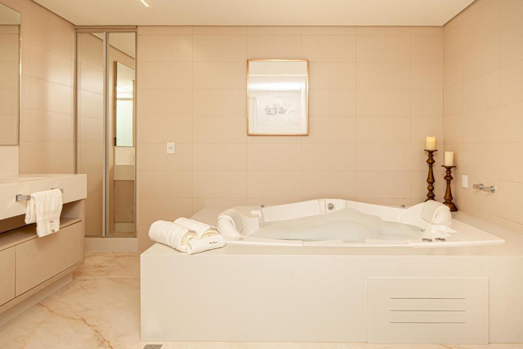 a white bathroom with a tub and a shower at Villa Toscana - Vale dos Vinhedos in Bento Gonçalves