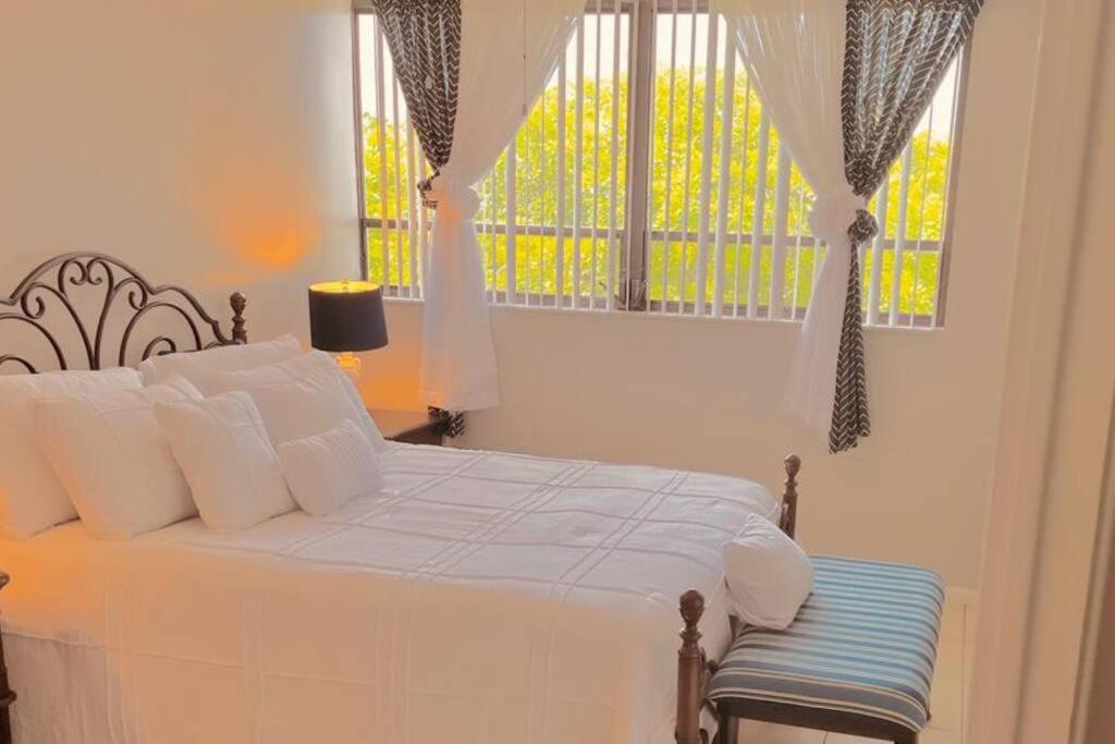 a bedroom with a bed with white pillows and a window at Shining Star in West Palm Beach