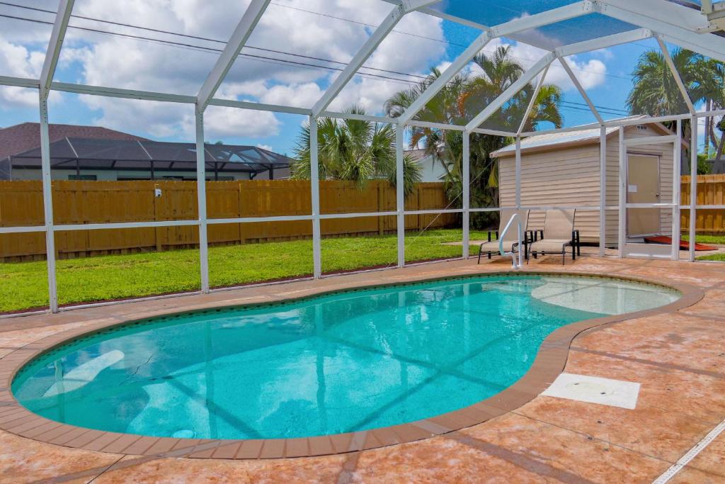 een zwembad in een tuin met een huis bij Beautiful Pool Home with Sleeping for 8 for LovelyPeople in Cape Coral