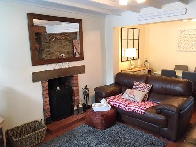a living room with a leather couch and a fireplace at Islas Cottage in Ystradgynlais