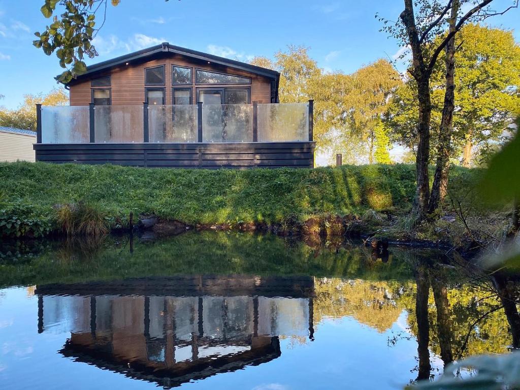 a house on a hill with a reflection in the water at Lakeview Lodge in Landford