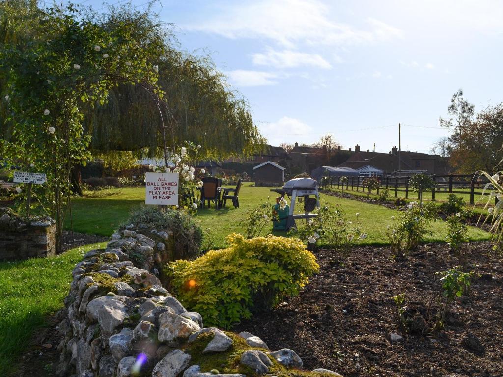 a garden with a stone wall and a sign at Pond Cottage - Ukc3736 in Bawdeswell