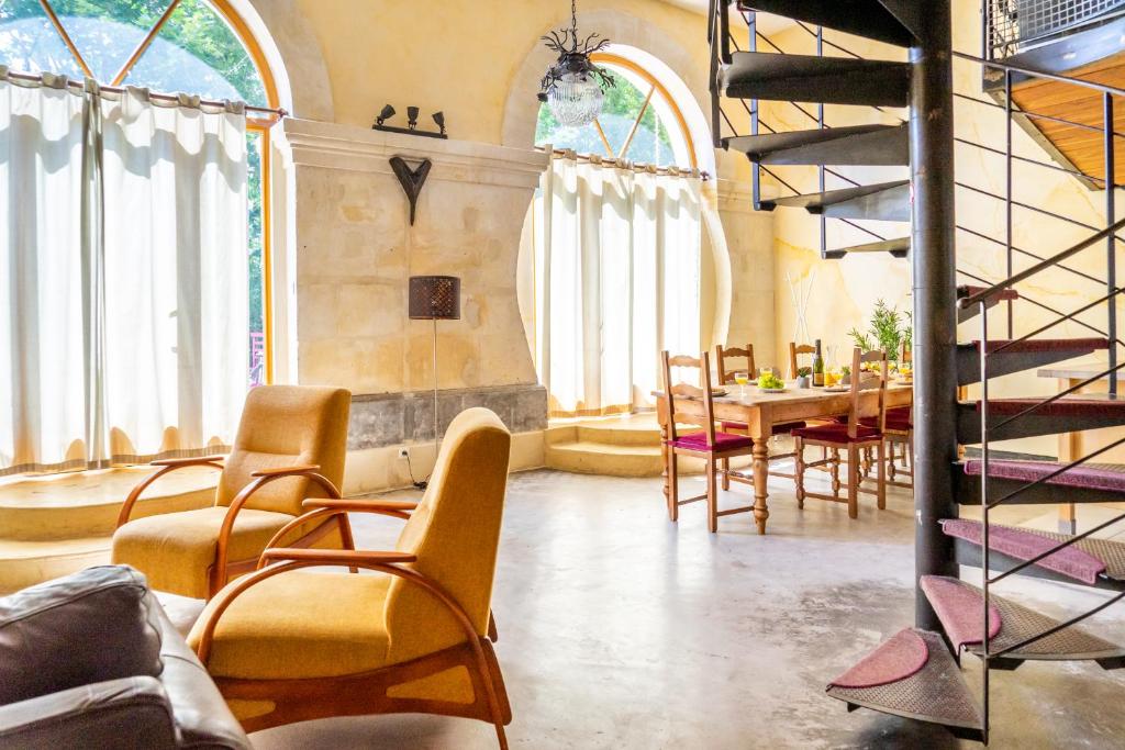 ペズナにあるUltimate Relaxation for Family or Group at Renowned Couvent des Ursulines, a Tranquil Escape in Historic Pézenasのテーブルと椅子、螺旋階段が備わる客室です。