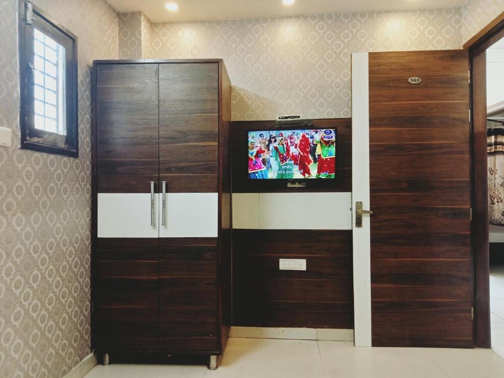 a room with two wooden doors and a flat screen tv at Hotel Robin Inn in Amritsar