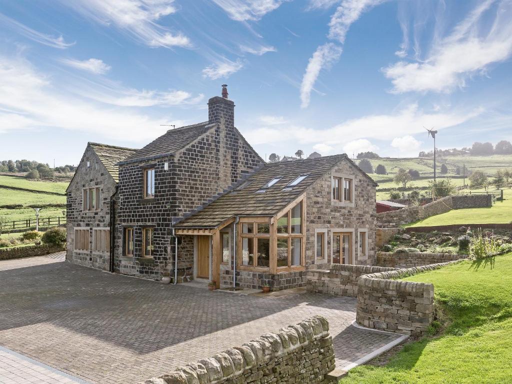 a large stone house with a stone wall at Sands Farm Cottage in Luddenden Foot