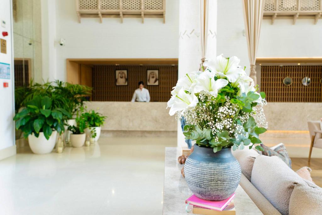 a vase filled with white flowers sitting on a table at Andalus Al Seef Resort & Spa in Abu Dhabi
