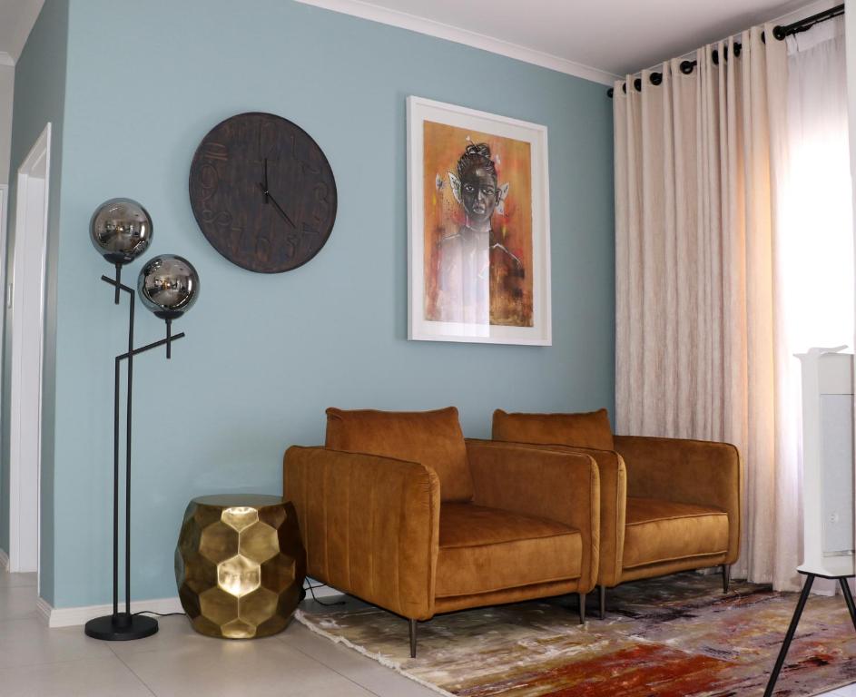 a living room with a couch and a clock on the wall at The Gold Portrait @ Carlswald in Midrand