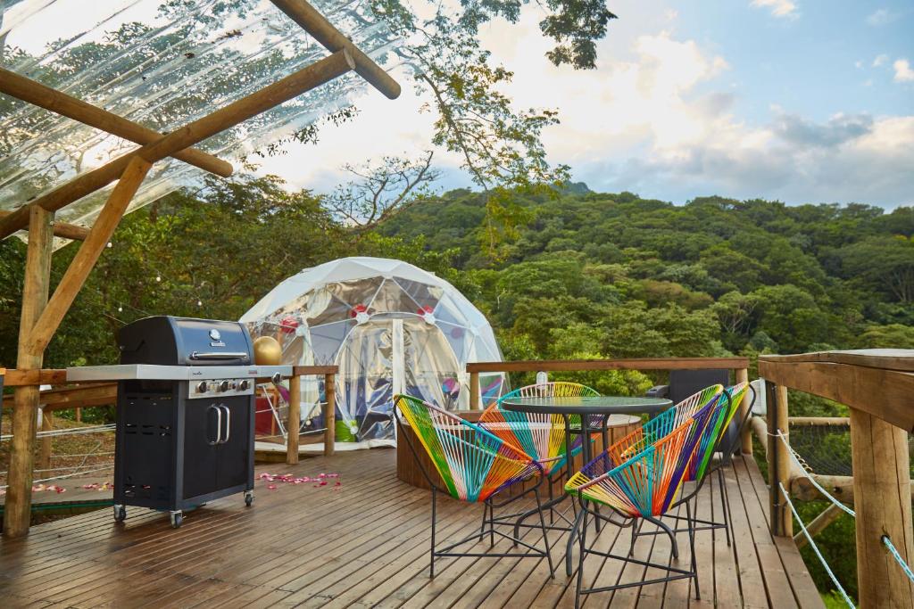 une terrasse avec un grill et des chaises ainsi qu'une tente dans l'établissement Glamping Itawa & Ecoparque turístico, à Villavicencio