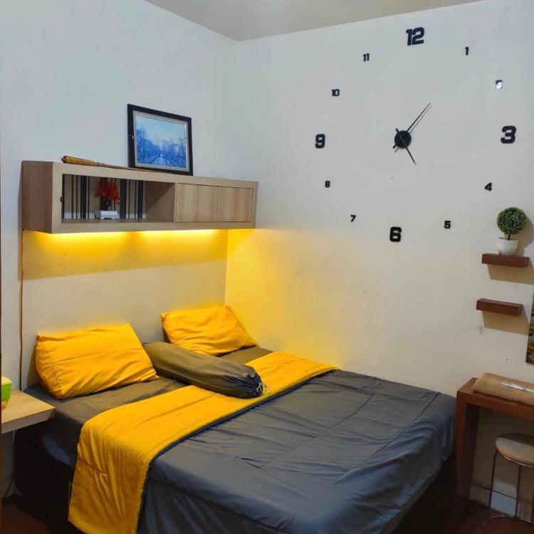 een slaapkamer met een bed met een klok aan de muur bij Salifa Rooms in Teko