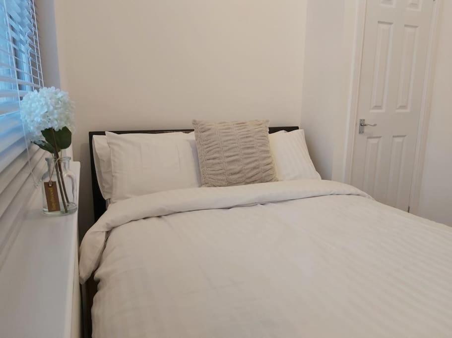 a bed with white sheets and pillows next to a window at Flat 7 - Newly Renovated in Portsmouth
