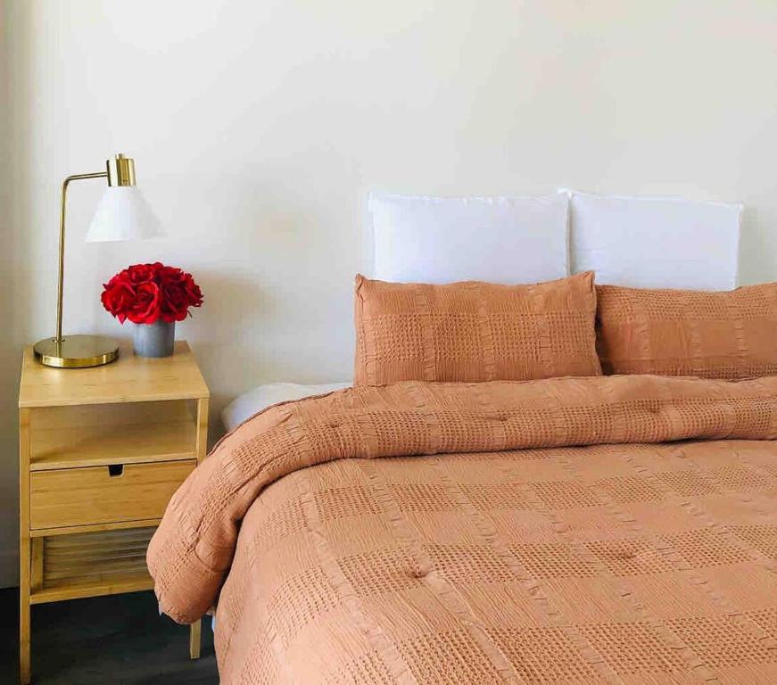 a bed with a orange comforter and a table with a lamp at Sky Apartment - Realm Adelaide in Adelaide