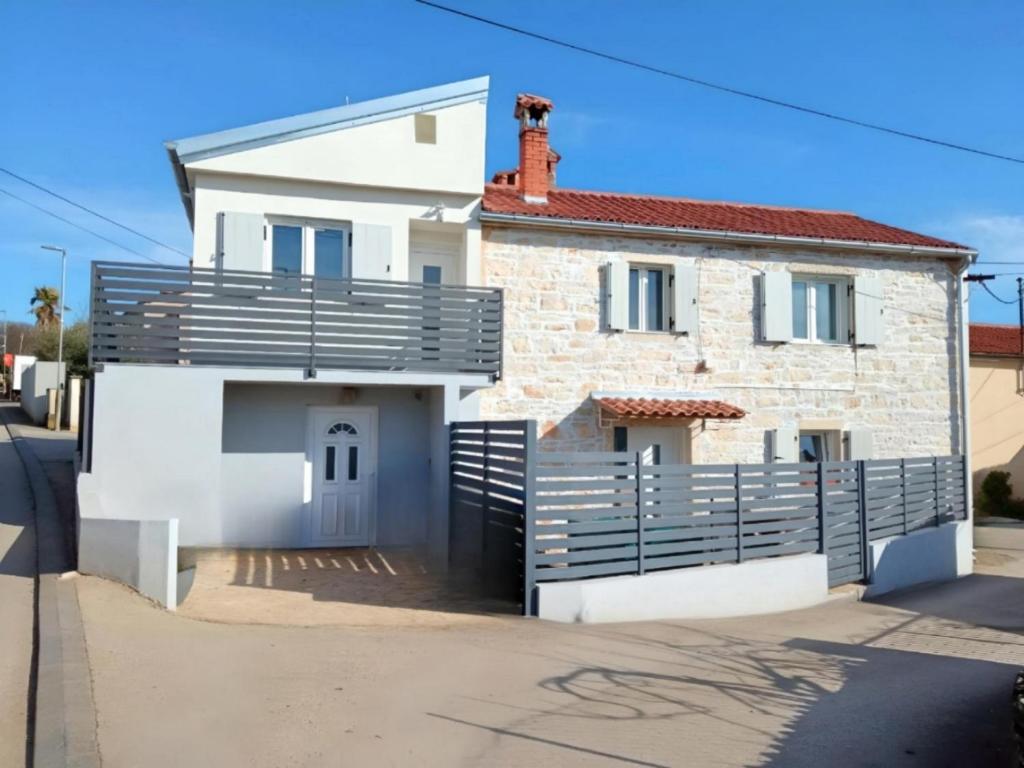 a white brick house with a black fence at Apartment Patrik in Vabriga