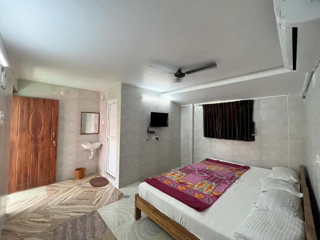 1 dormitorio con 1 cama y TV. en Royal Grand Residency, en Pondicherry