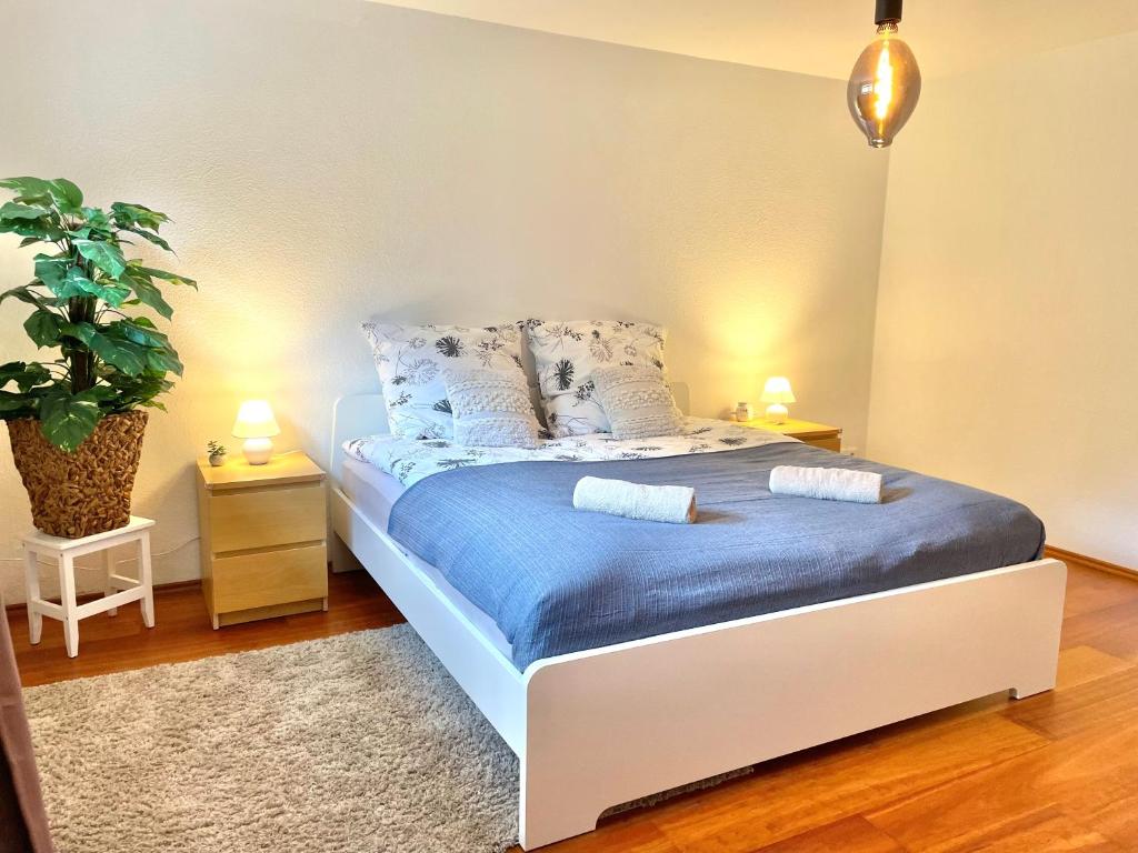 ein Schlafzimmer mit einem Bett mit blauer Bettwäsche und einer Pflanze in der Unterkunft Entspannte Souterrain Wohnung in Munster im Heidekreis