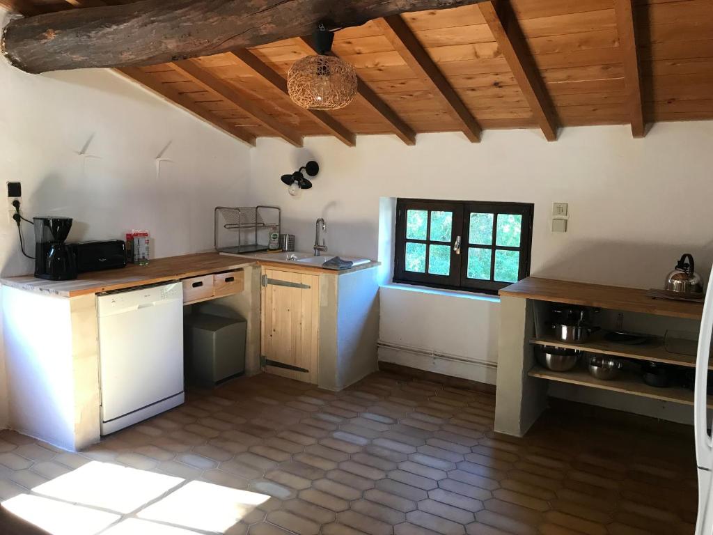 uma cozinha com electrodomésticos brancos e um tecto de madeira em Gîte en pierre au cœur des chiens de traîneau em Mirmande