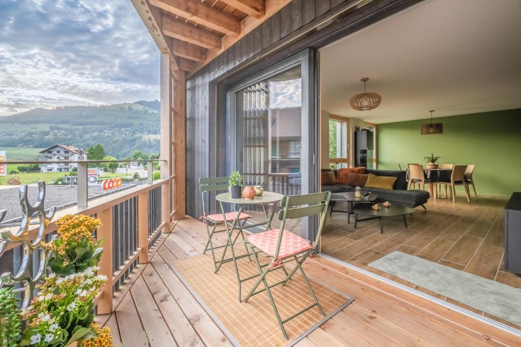 un patio con mesa y sillas en una terraza en Un écrin face aux bains en Charmey