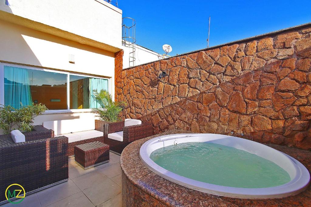 y baño con bañera en una pared de piedra. en Linda cobertura com jaccuzzi e terraço, en Río de Janeiro