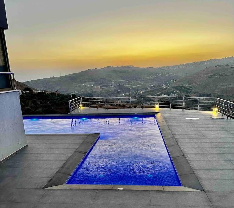 uma grande piscina com água azul num edifício em Farmhouse with Pool and Breathtaking Views em Amã