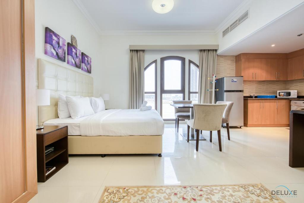 Cet appartement comprend une chambre avec un lit et une cuisine avec une table. dans l'établissement Elegant Studio at DAMAC Lincoln Park A Arjan-Dubailand by Deluxe Holiday Homes, à Dubaï