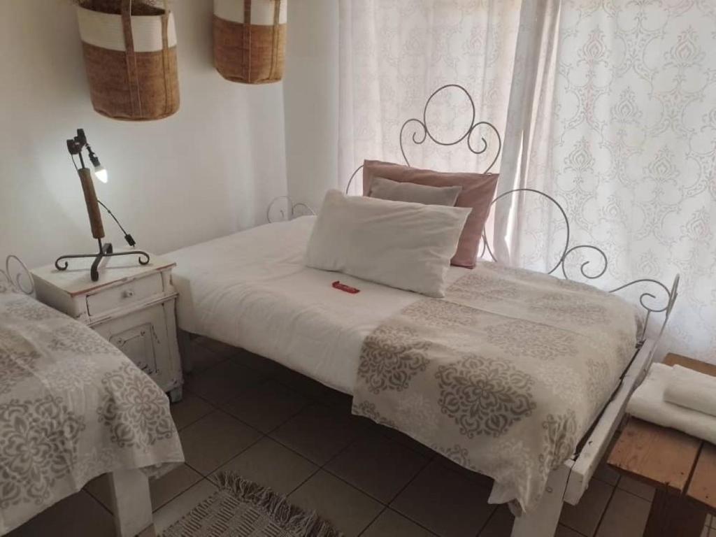 ein Schlafzimmer mit 2 Betten und einer Lampe auf einem Tisch in der Unterkunft Whimsical in Groutfontein