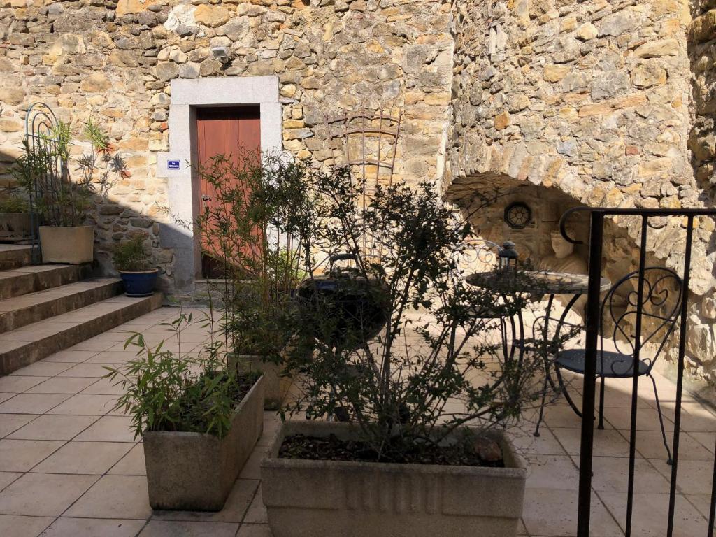 Un edificio de piedra con una puerta y algunas plantas. en LA PATISSERIE, en Saint-Sauveur-de-Cruzières