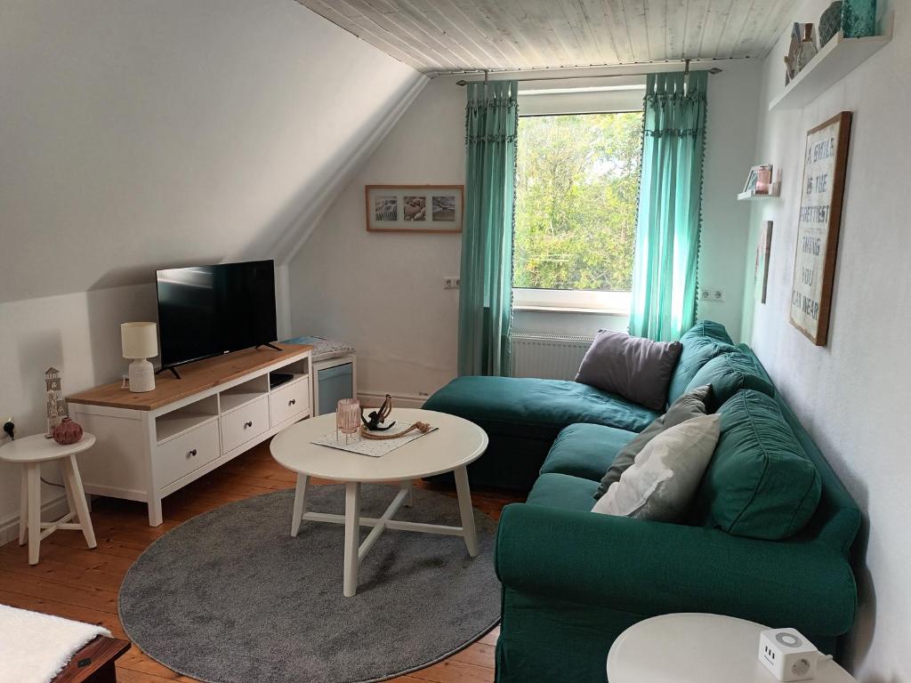 un soggiorno con divano verde e tavolo di De Dackluuk a Wittmund