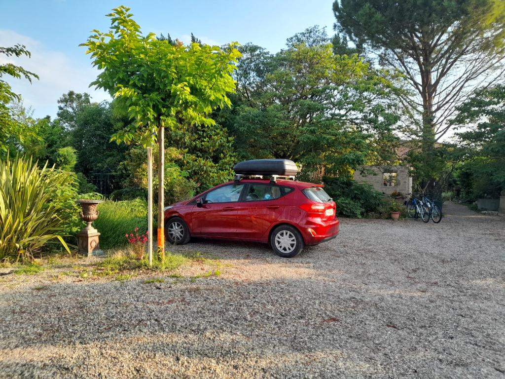a small red car parked next to a tree at le jardin in Montélimar