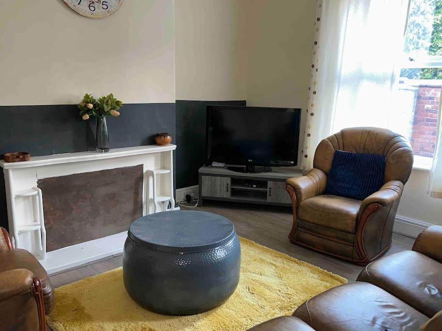 a living room with a tv and a couch and chairs at Clevedon House in Manchester