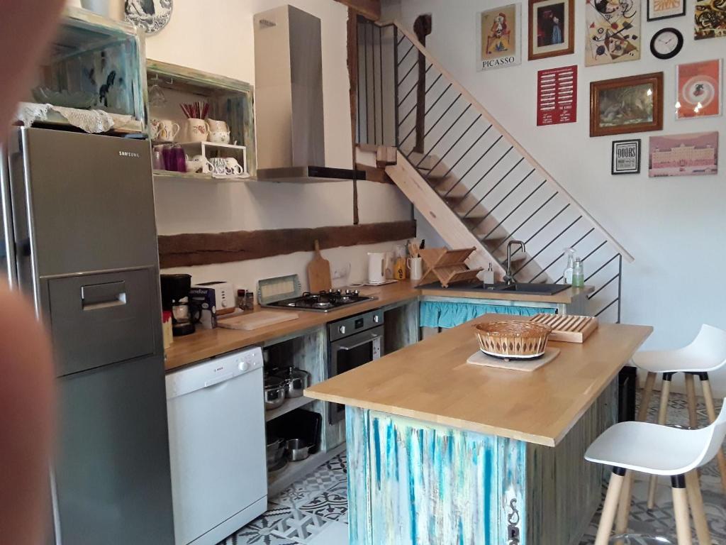 a kitchen with a refrigerator and a table and a staircase at Gite La Pipistrelle 