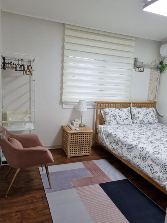a bedroom with a bed and a chair and a window at Hongdae Sky View Private Roof Garden House 2BR 2QB 1SSB Free WIFI Starbucks Capsule 외국인전용 in Seoul