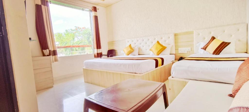 ein Hotelzimmer mit zwei Betten und einem Fenster in der Unterkunft Sanjog Resort in Kota
