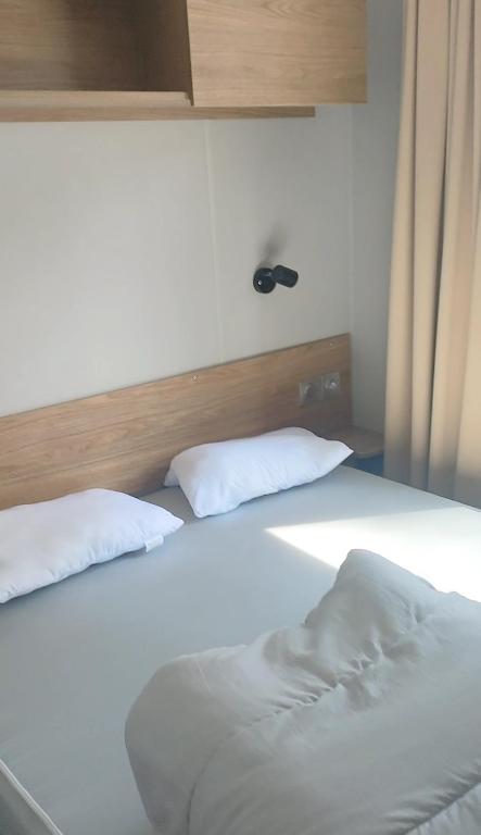Una cama blanca con dos almohadas encima. en Mobil home spacieux, en Seignosse