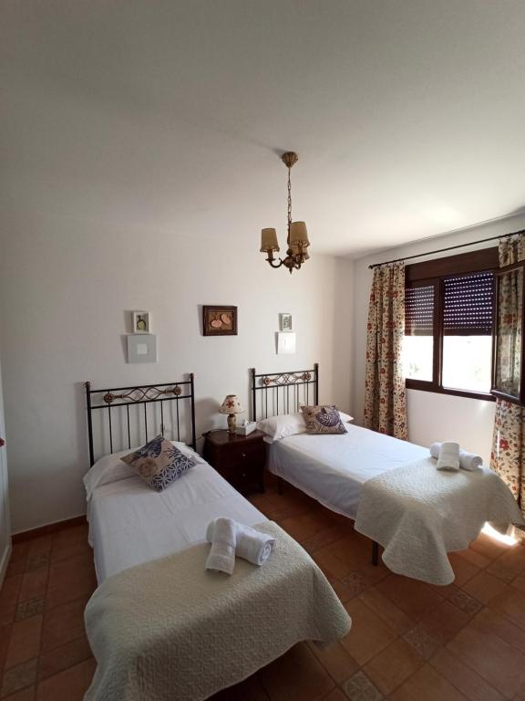 1 dormitorio con 2 camas y ventana en Villa Cuatro Encinas, Iznájar, en Iznájar