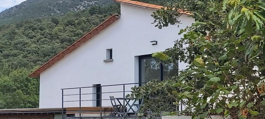 Casa blanca con balcón frente a una montaña en LE REFUGE DES CASCADES en Vernet-les-Bains
