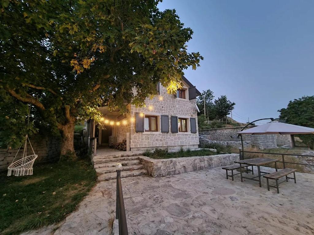 a stone house with a picnic table and an umbrella at Guest House Lovcen in Cetinje