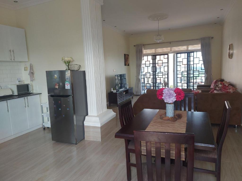 una cucina e un soggiorno con tavolo e frigorifero di Beautiful 2-Bed Apartment in Akright City Bwebajja a Namulanda