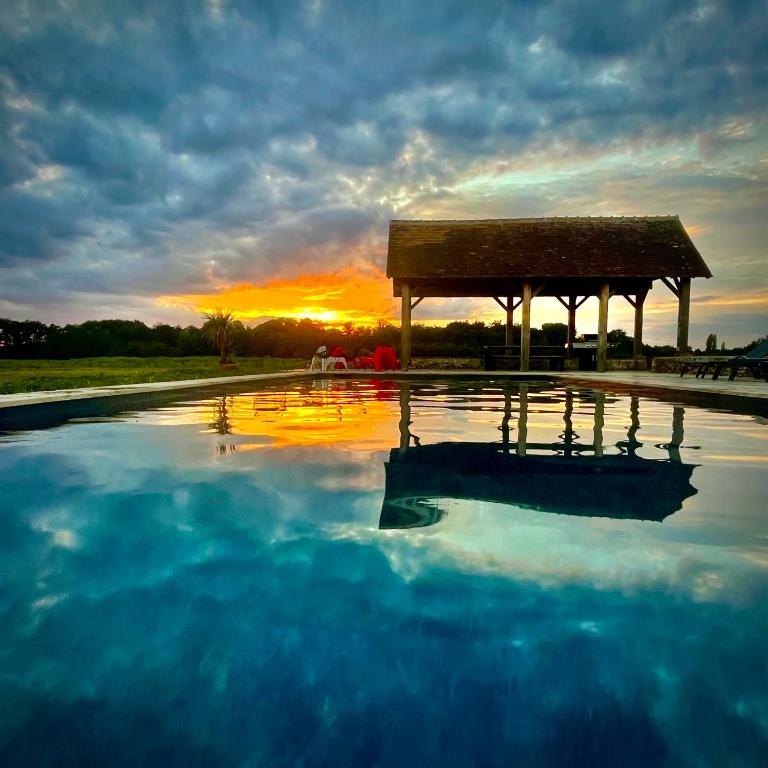 - une grande piscine d'eau avec un kiosque au coucher du soleil dans l'établissement La Michellière à Continvoir, à Continvoir