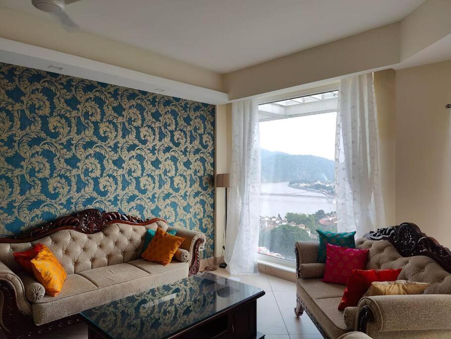 a living room with a couch and a window at The Ganges View Luxury Penthouse by iTvara in Rishīkesh