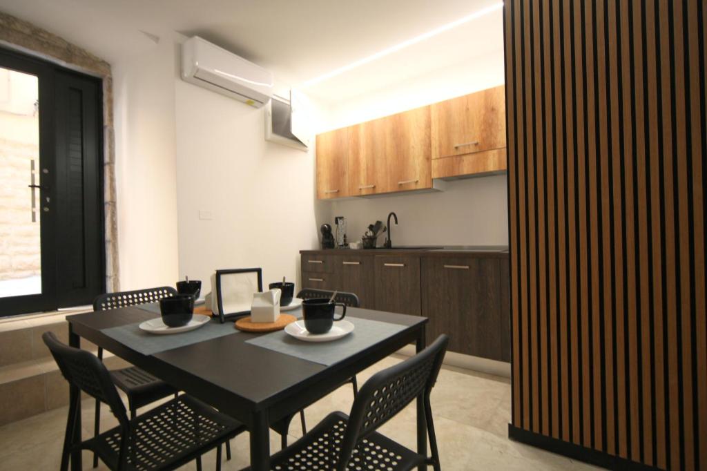 a kitchen with a black table and chairs in a room at Maison De Ruelle in Barletta