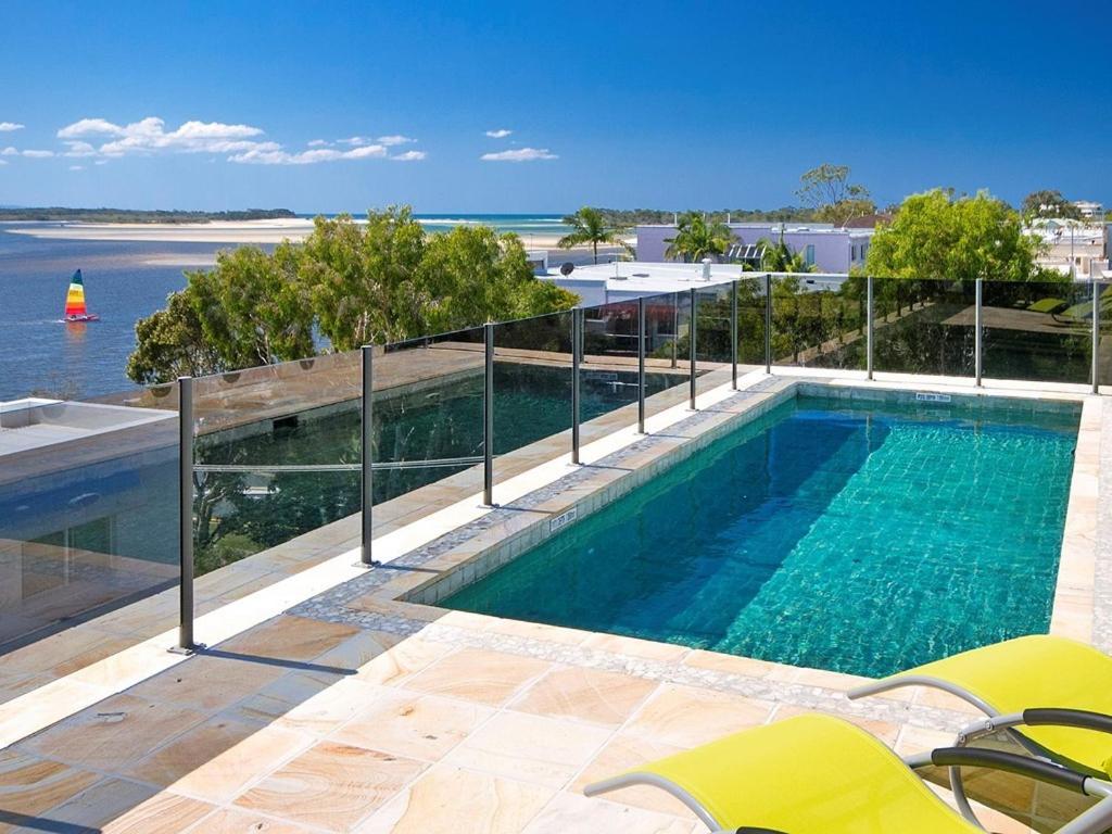 a swimming pool with a view of the ocean at Noosa Dua Apartment 2, Noosaville in Noosa Heads