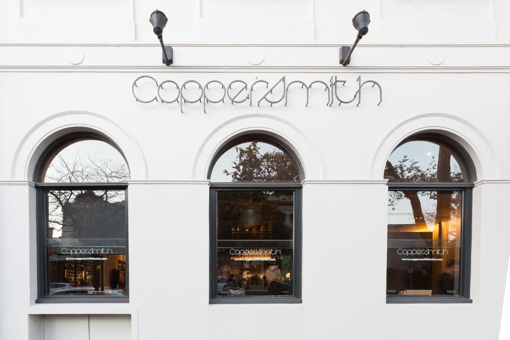 a white facade of a store with three windows at Coppersmith Hotel in Melbourne