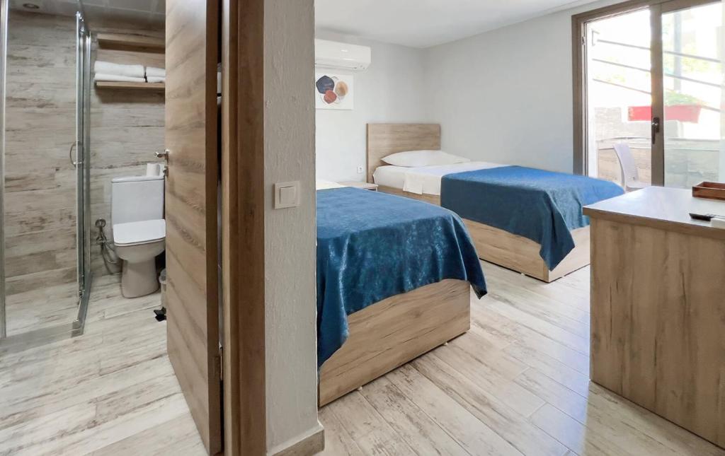 two beds in a room with a shower and a bathroom at eYLÜL 16 OTEL in Çeşme