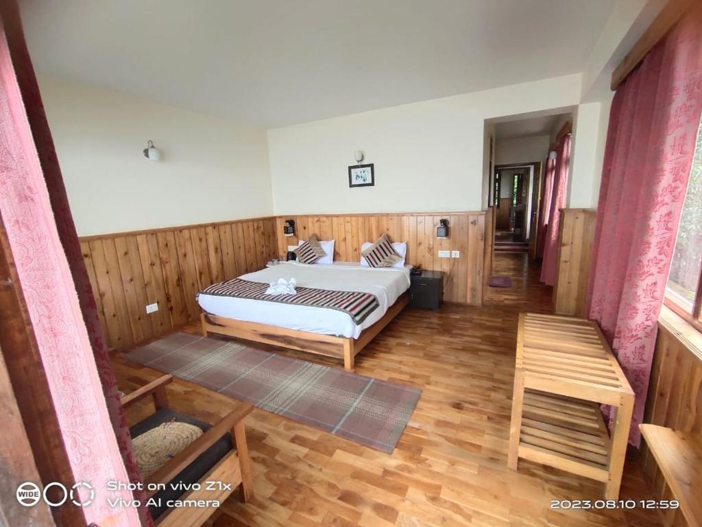 a bedroom with a bed and a wooden floor at Hotel Hidden House (Fair View) in Pelling