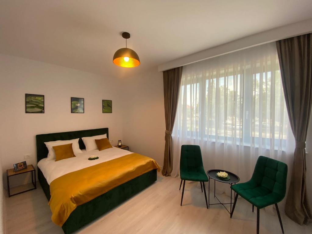 a bedroom with a bed and two green chairs at Vila Moga in Sînmartin