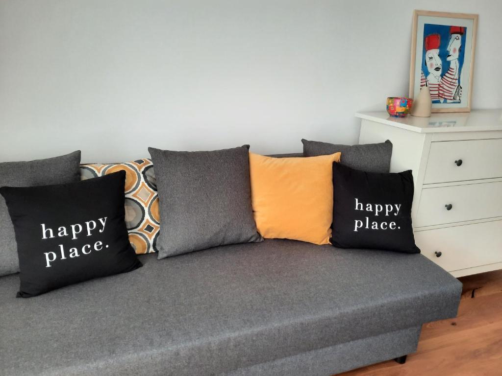 un sofá con un lugar feliz almohadas en él en Happy Place, en Ig