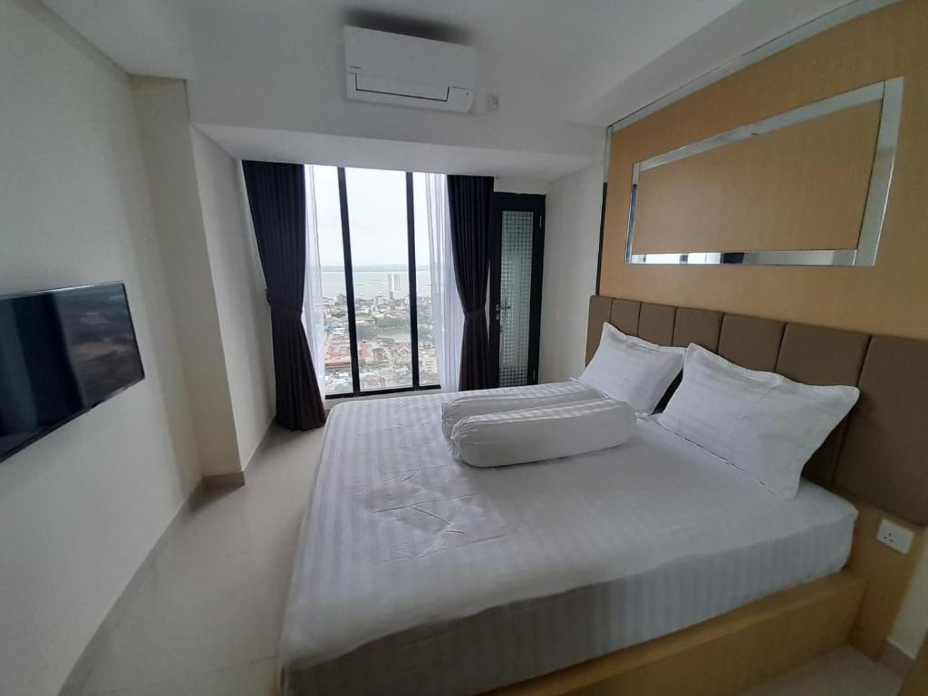 a bedroom with a large bed with a large window at Lenggo - Apartement Meisterstadt Pollux Habibie 52-05 in Kangboi