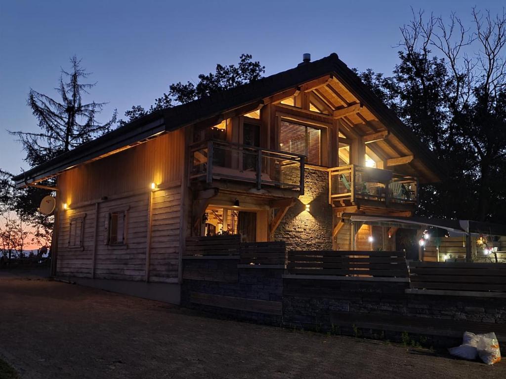 a large wooden house with a balcony at night at Chalet des secrets in Lyaud