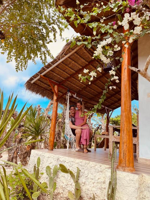 two people sitting in a swing on a porch at kaje cottage & restaurant in Nusa Penida
