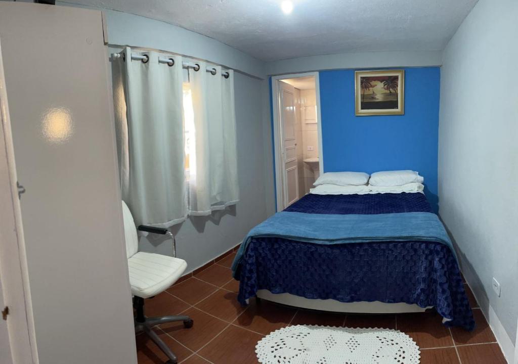 a blue bedroom with a bed and a chair at Dith's House (kitnet 1) in Campos do Jordão